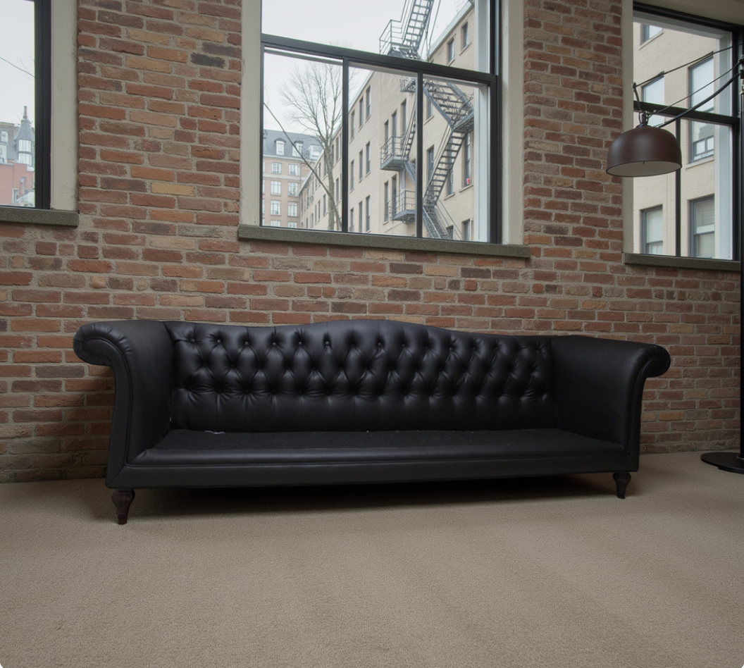 Black leather Chesterfield sofa in a brick loft